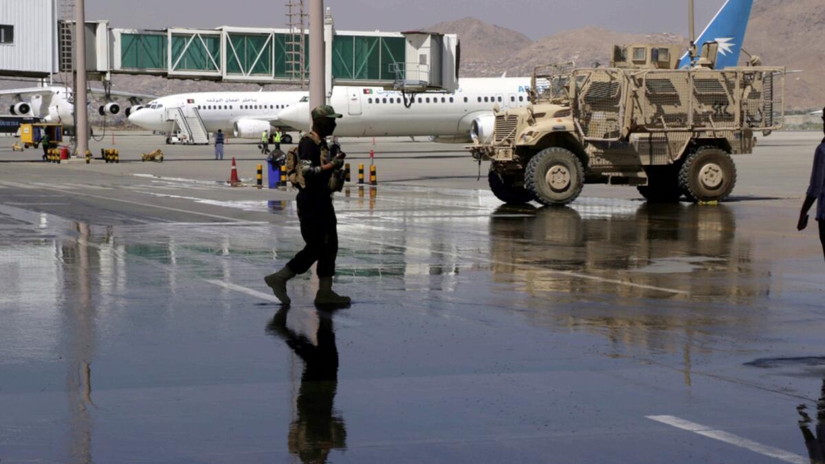 A Taliban soldier walks on the tarmac near parked planes at Hamid Karzai International Airport in Kabul. — AP
