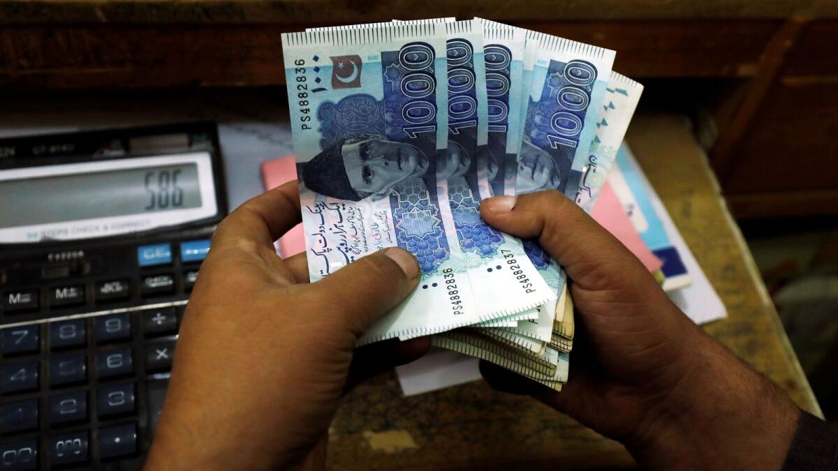 A trader counts Pakistani rupee notes at a currency exchange booth in Peshawar. The workers’ remittances stayed above $2 billion for a record 22nd consecutive month in March. — File photo