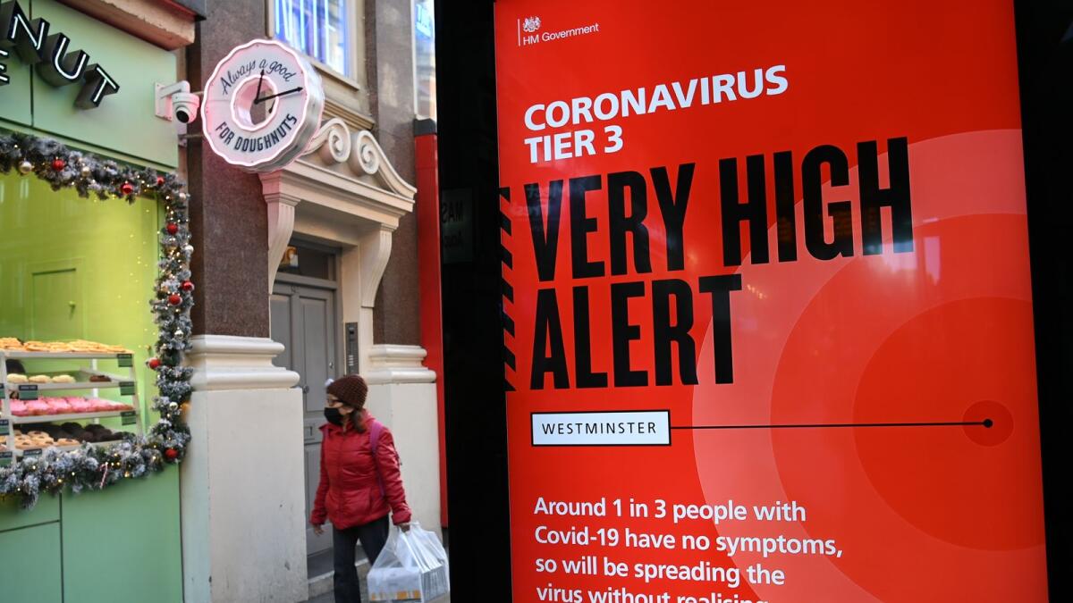 A pedestrian walks past an electronic billboard with a government message displaying the current Coronavirus Tier 3 alert level in central London on December 17, 2020.