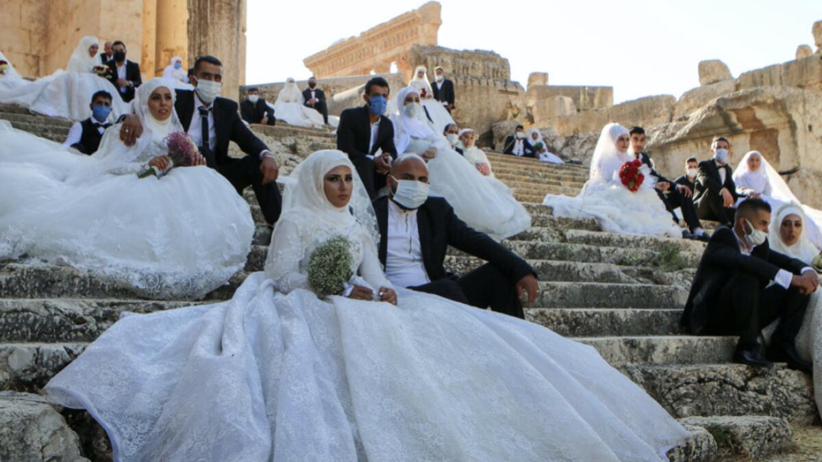 Lebanese couples, wearing protective face masks, sit on the steps during a group wedding at the Temple of Bacchus at the historic site of Baalbek in Lebanon's eastern Bekaa Valley, during the coronavirus pandemic. Photo:  AFP