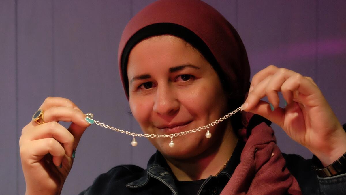 Bassant Bader, an exhibitor holds pearl necklace at a traditional shop during the cultural event.