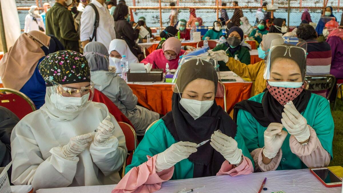 Doctors prepare syringes with the Sinovac Covid-19 coronavirus vaccine at a makeshift mass vaccination clinic on a football field in Surabaya, East Java, Indonesia, on Tuesday as the Southeast Asian nation battles an unprecedented wave of new infections.