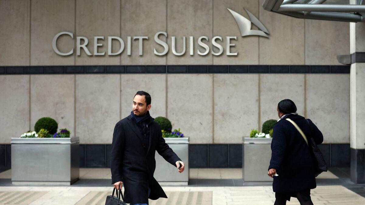 People walk past the Credit Suisse office in Canary Wharf in London on Monday. - Reuters
