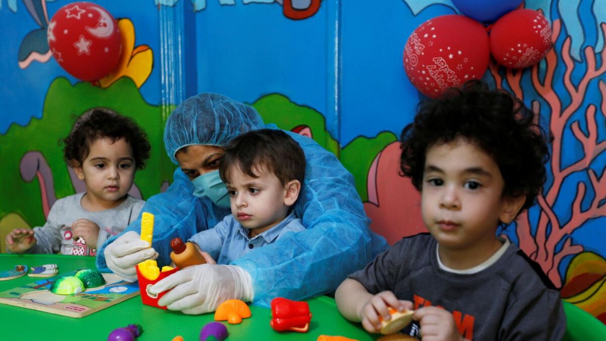 A teacher wearing a protective suit interacts with the children at a nursery in Amman, Jordan, October 22, 2020.