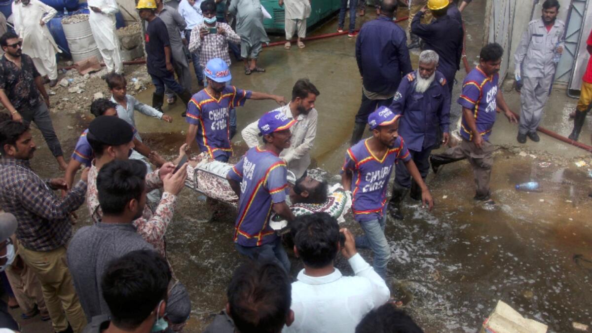 Rescue workers transport an injured person after recovering him from a burnt chemical factory, in Karachi. Photo: AP