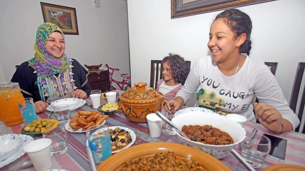Salma preparing special dishes for Iftar at her home in Al Qusais, Dubai, and (right) Salma with her daughters,  Shaima and Shahad, during Iftar.  — Photos by Dhes Handumon
