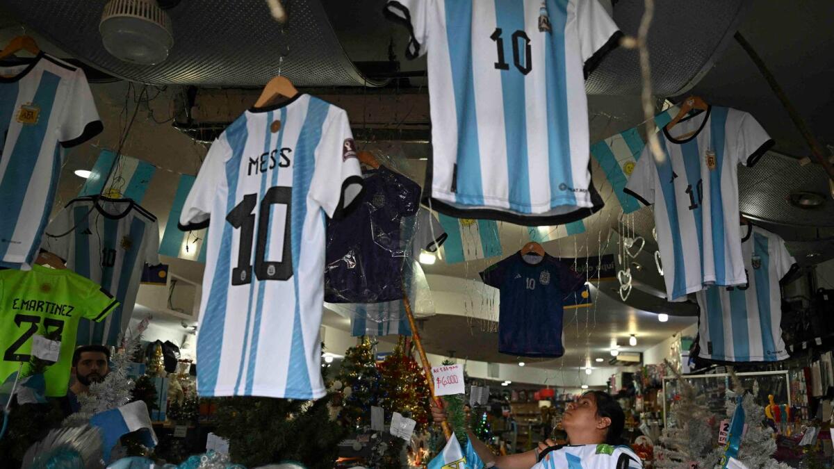 A woman organises T-shirts of the Argentine national football team inside a store in Buenos Aires. — AFP